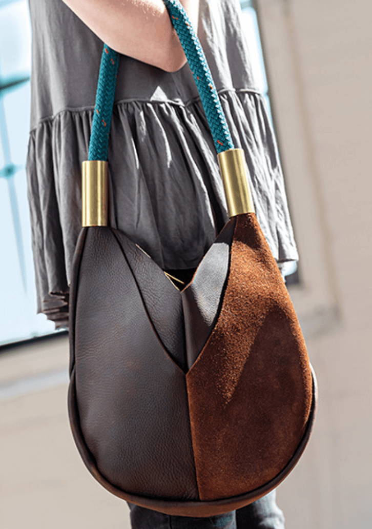 closeup on leather bag with teal strap held by woman