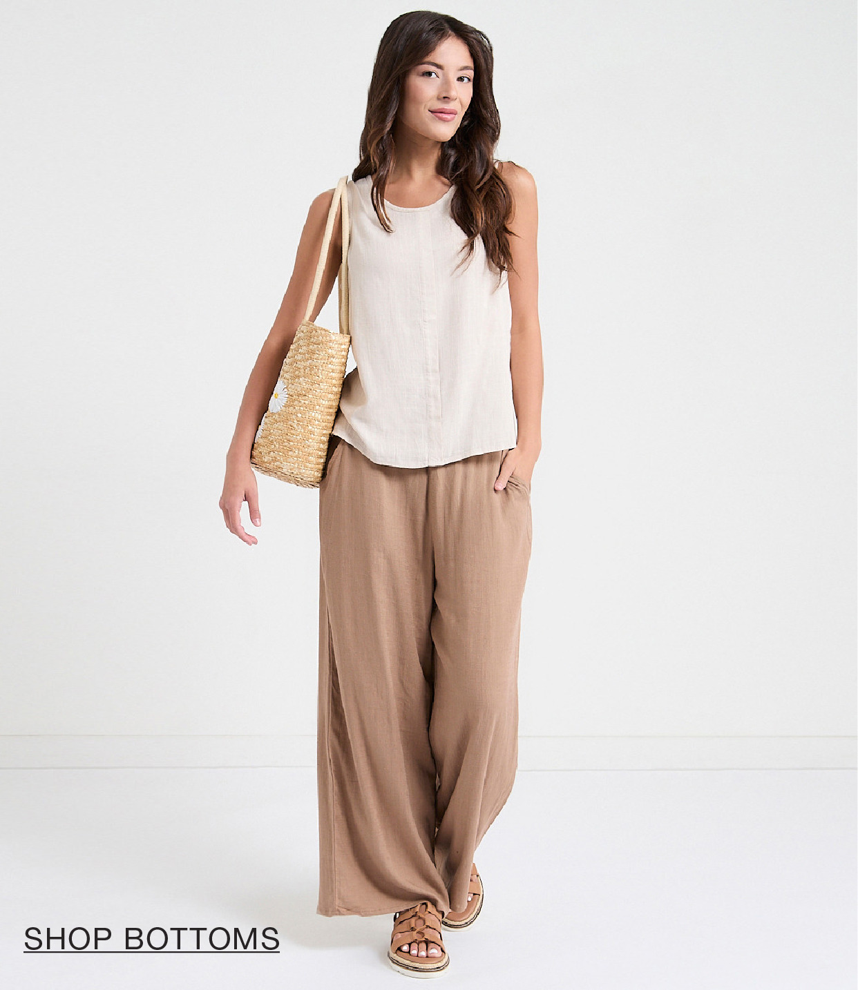 Woman in casual outfit with bag, walking in a light background.