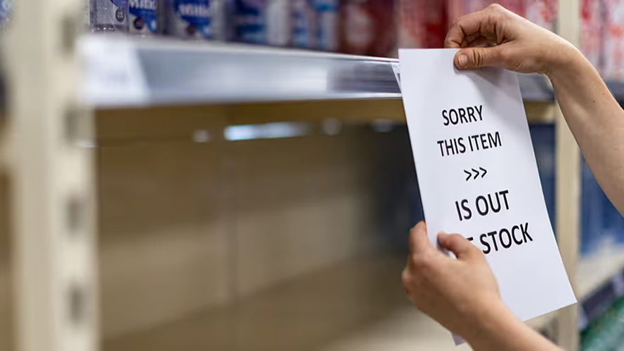 Person placing an out-of-stock sign on a shelf in a store.
