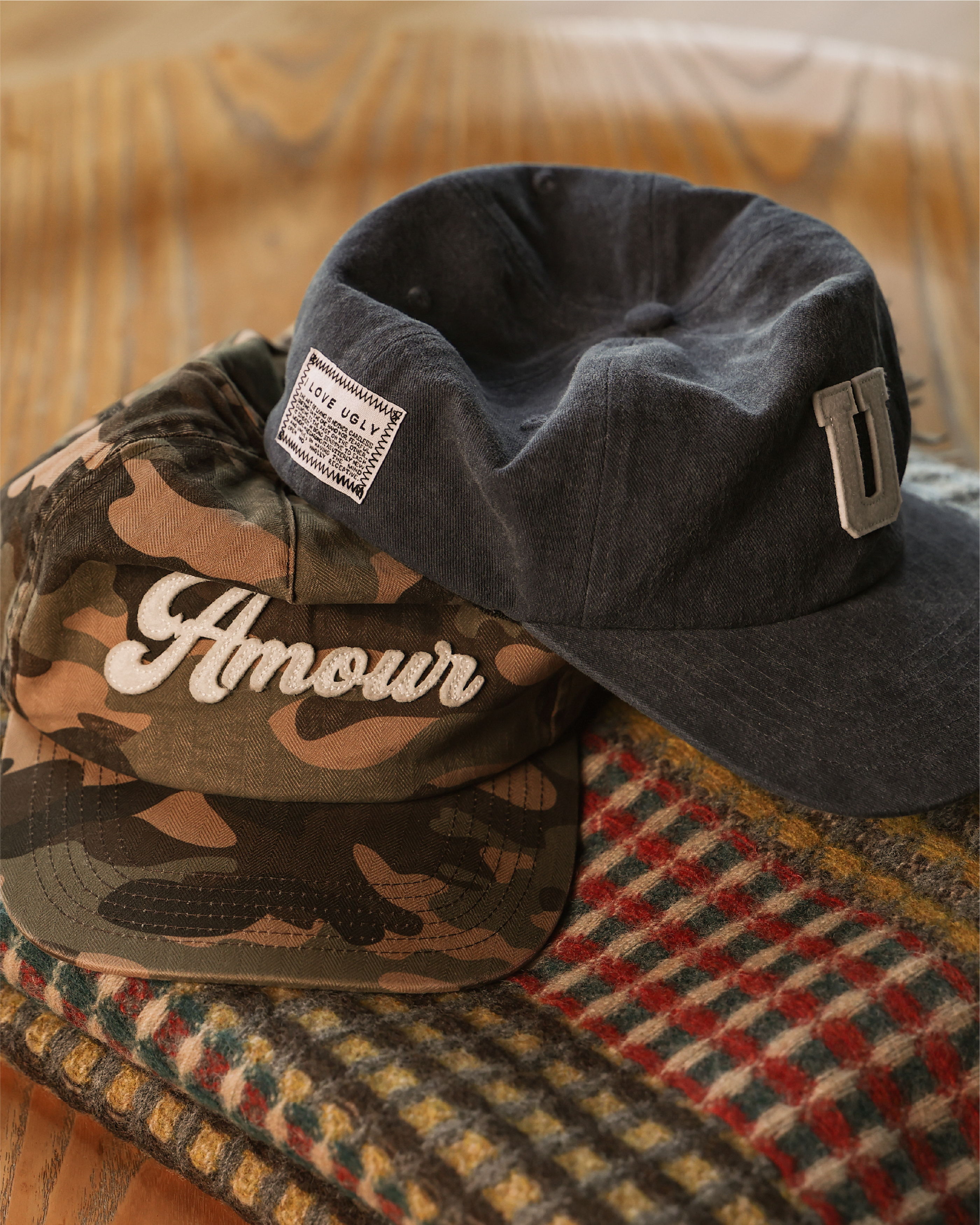 Two hats on a patterned fabric background. One is camo, the other denim.