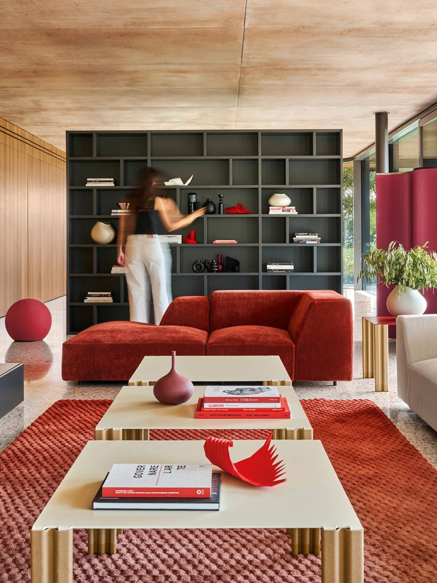 A modern BALERI ITALIA living room with a woman organizing a black bookshelf.