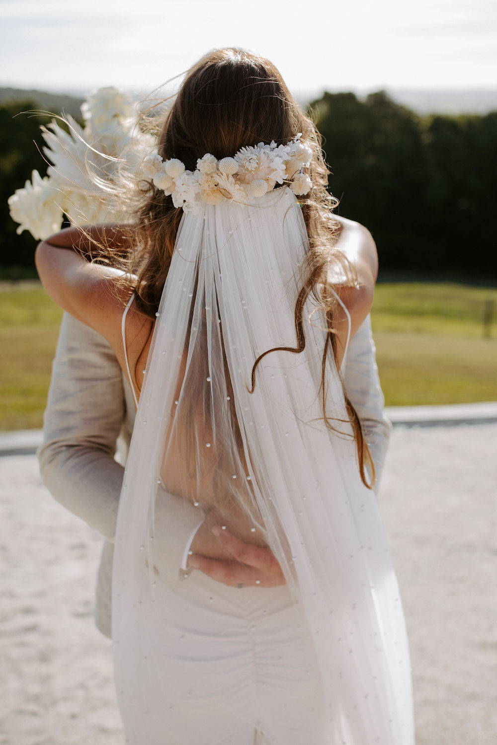 Bride wearing the Grace Loves Lace long pearly veil hugging her new husband