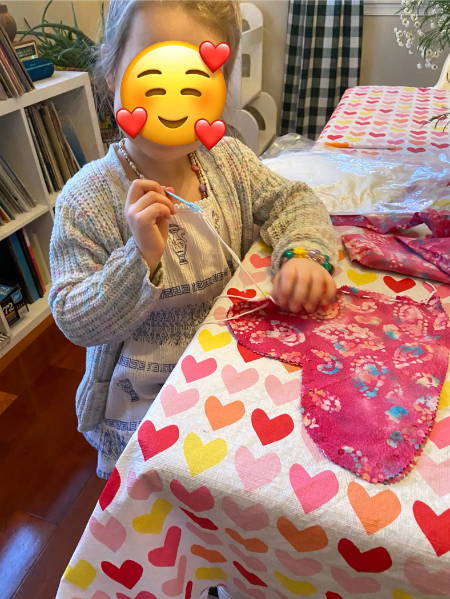 little girl sewing a heart pillow