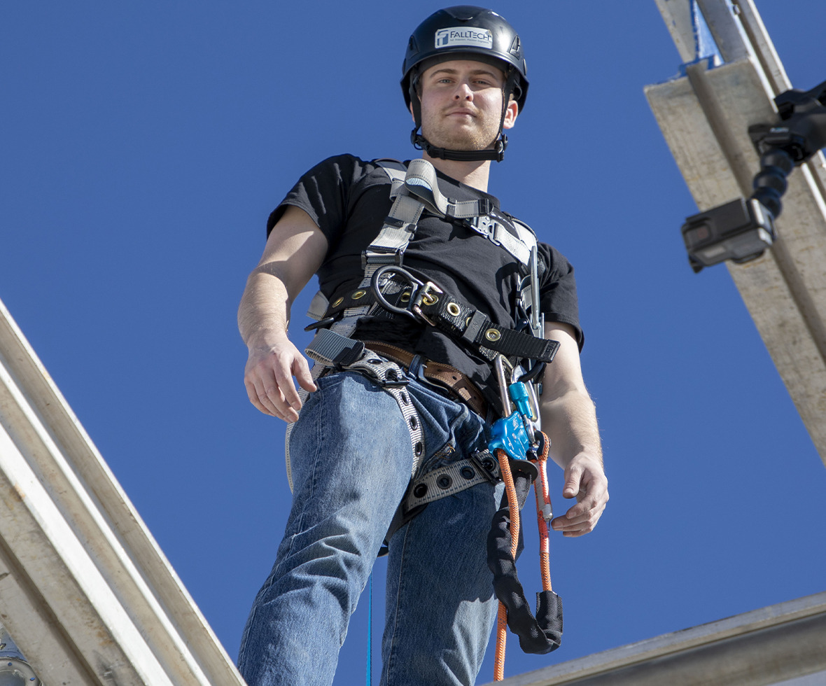 Construction worker looking down from a building with a rope positioning connector attached to his harness