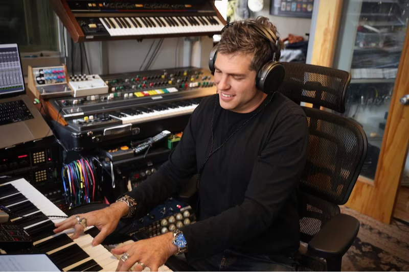 Person playing piano in a music studio with headphones on.