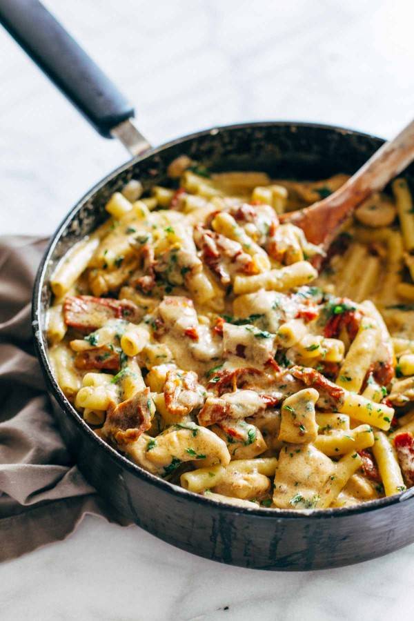 Ziti pasta in a cheesy sauce with sun dried tomatoes prepared in a pan