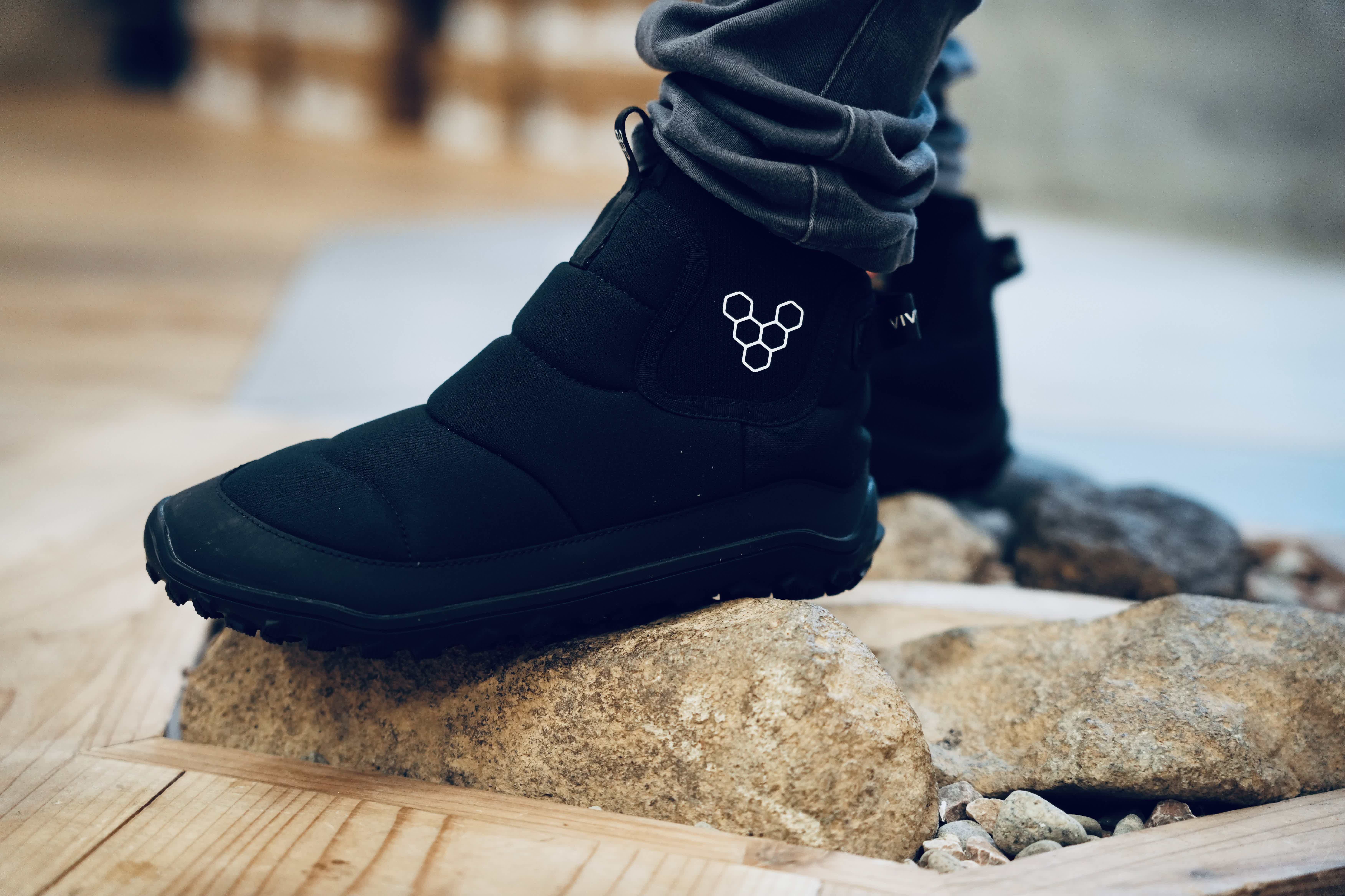 A person wearing black boots standing on a stone floor.
