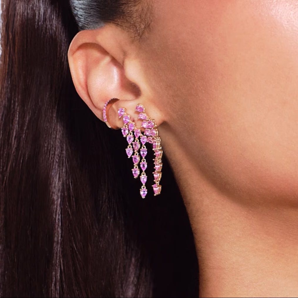 Close-up of a woman's ear wearing elegant pink dangling earrings.