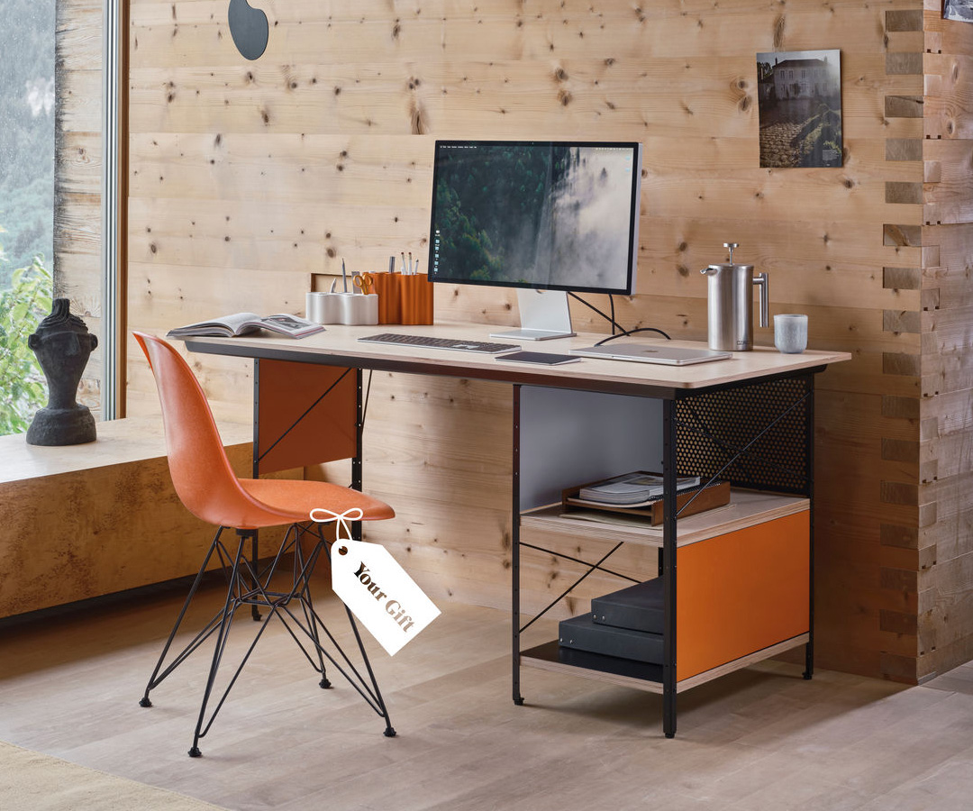 Modern workspace with a Vitra desk, chair, and computer against a wooden wall.