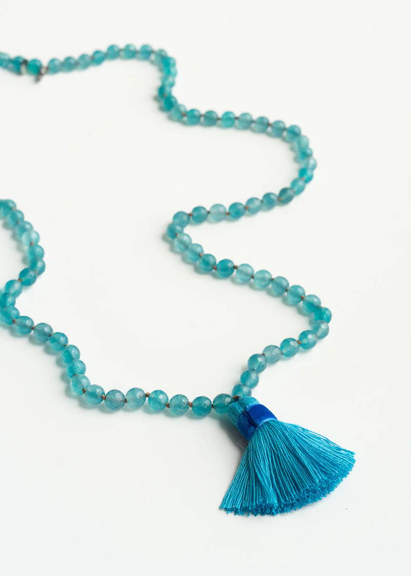 A aqua blue glass bead necklace with a matching tassle pendant