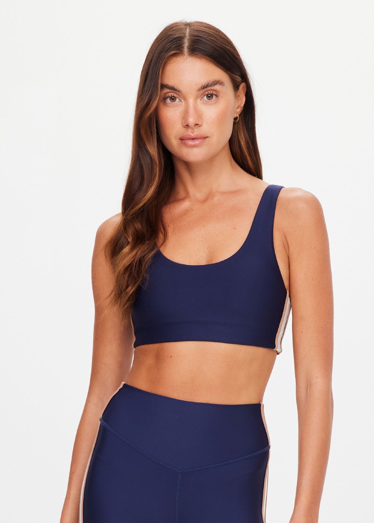 Woman wearing a navy sports bra and matching leggings, posing confidently.