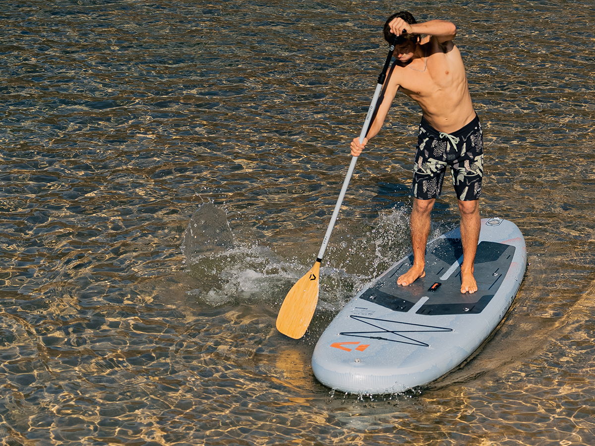 A person paddleboarding on calm water.