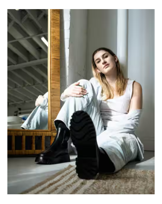 Person sitting on the floor, wearing casual attire, with a mirror in background.