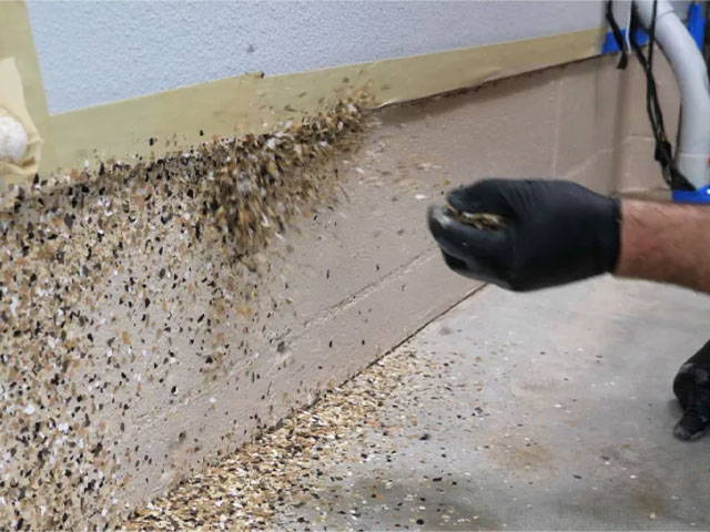 Evenly sprinkling flake onto garage walls, removing excess with a putty knife, and preparing for moisture seal application.