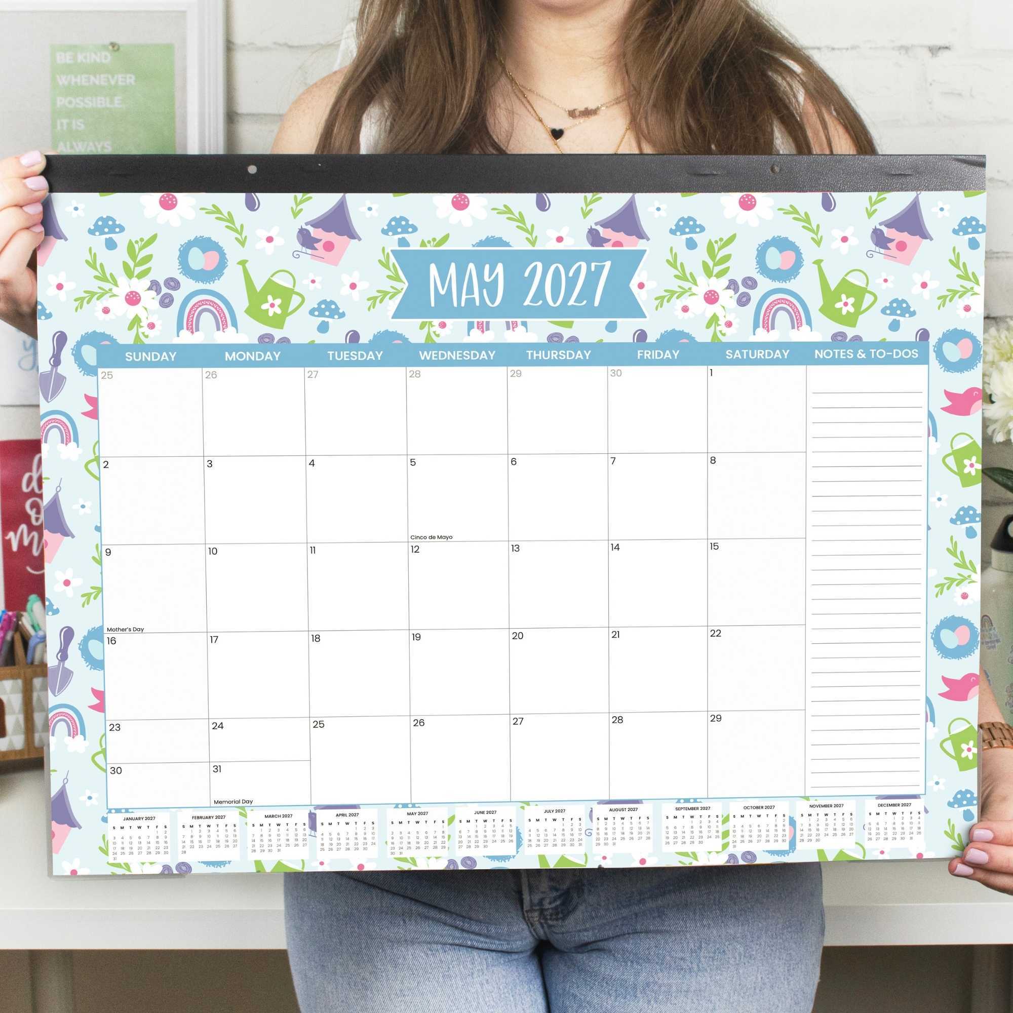 a large, colorful 2027 calendar being held by a woman