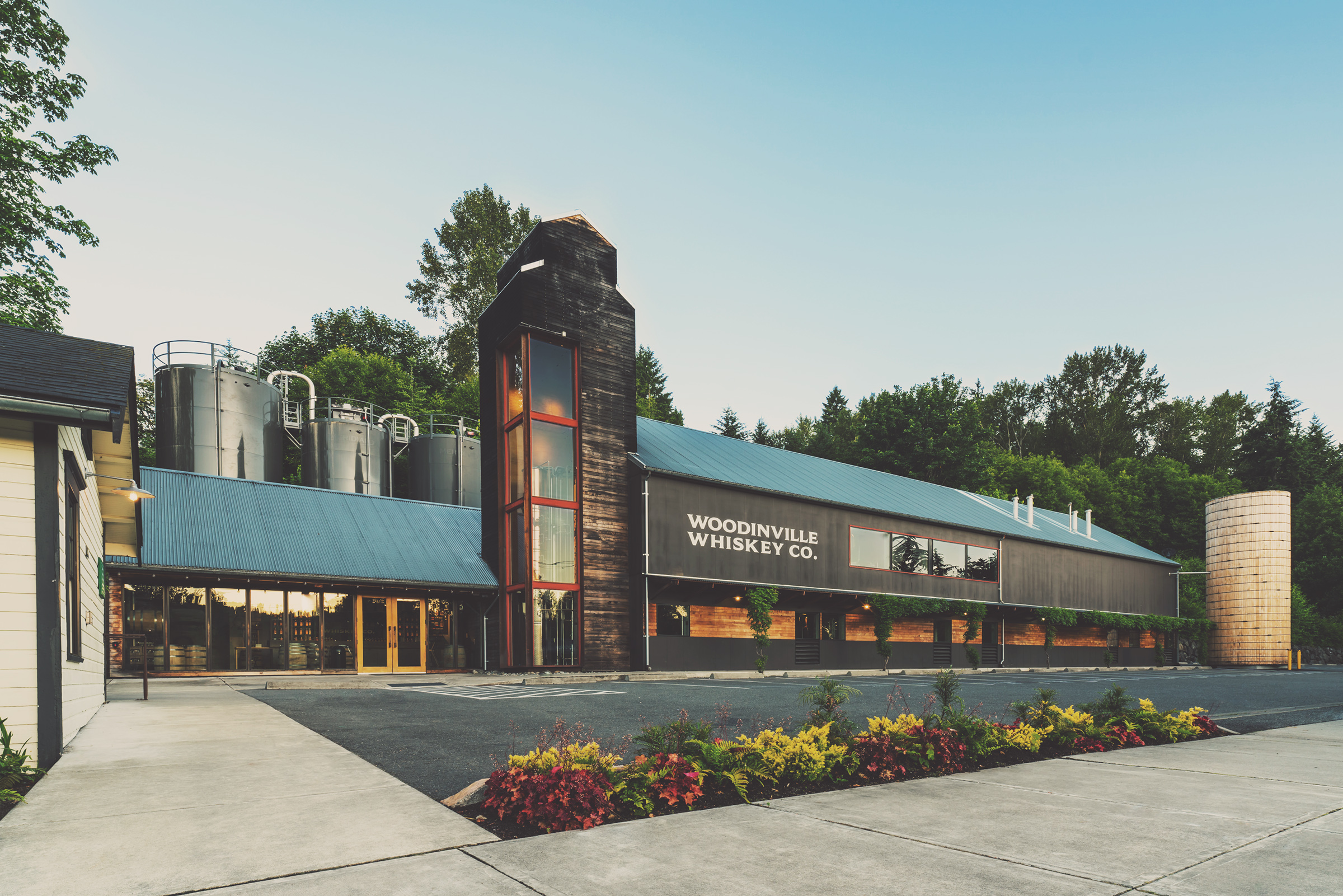 Modern building with landscaping and silos against a clear sky.