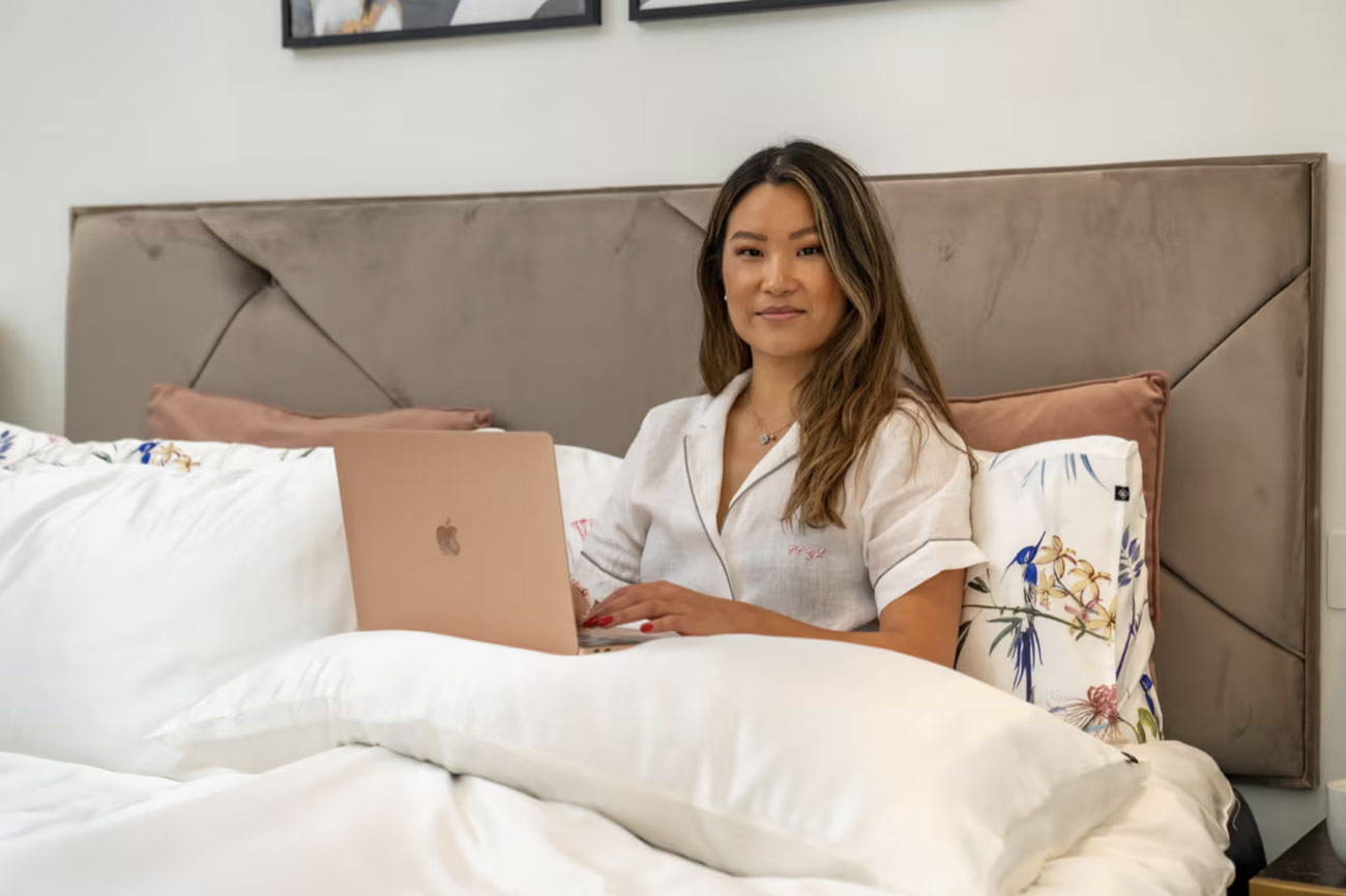 woman sitting in silk sheets with laptop computer