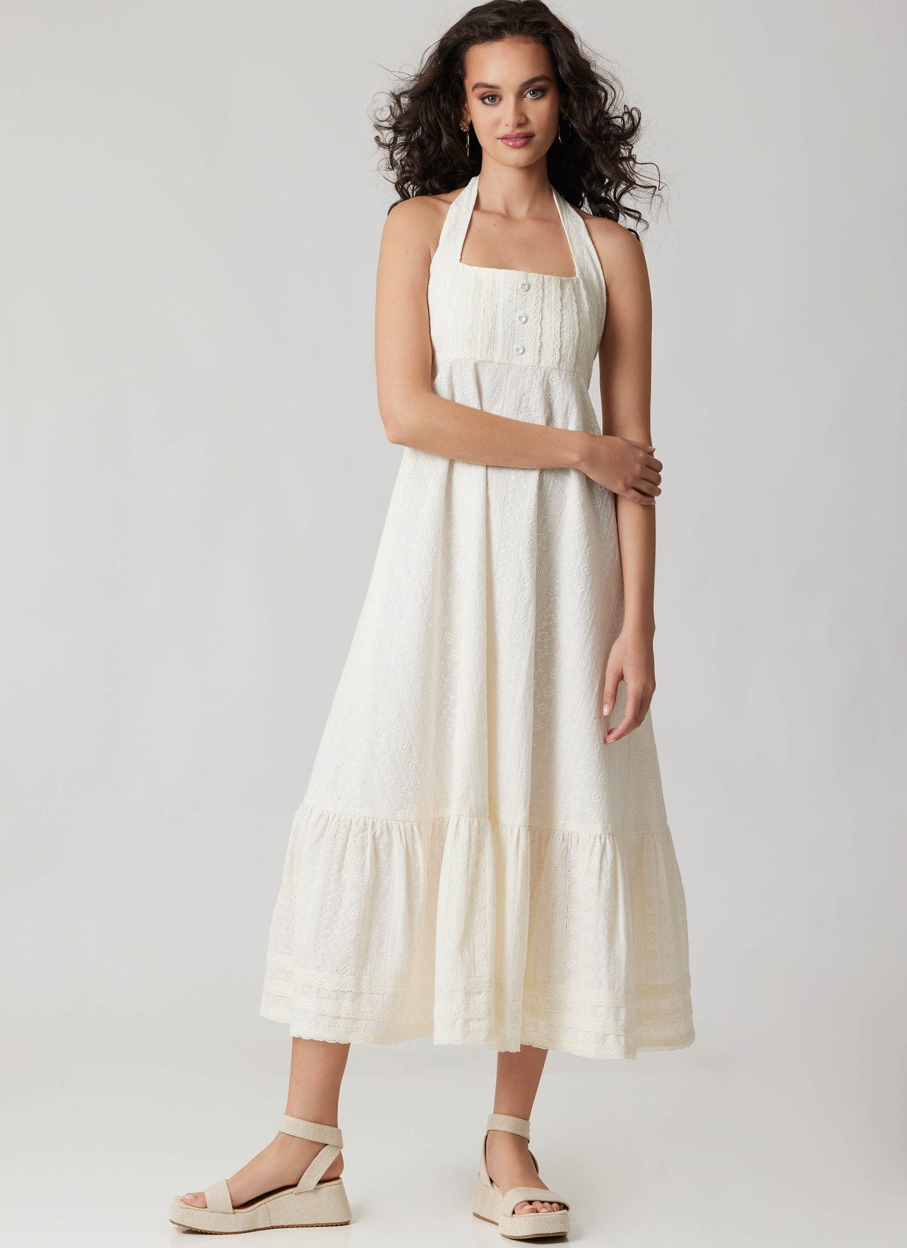 Model wearing a white halter dress with a tiered skirt.