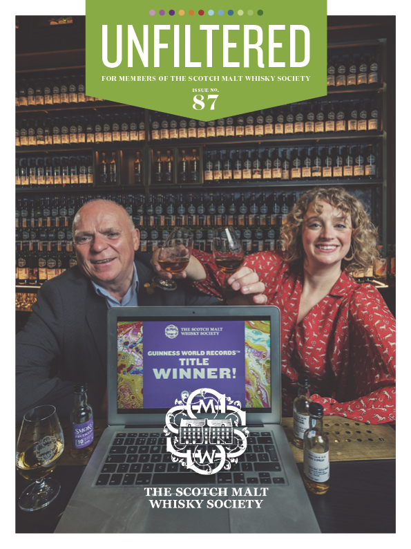 Man and woman celebrating a whisky award, with bottles in the background.