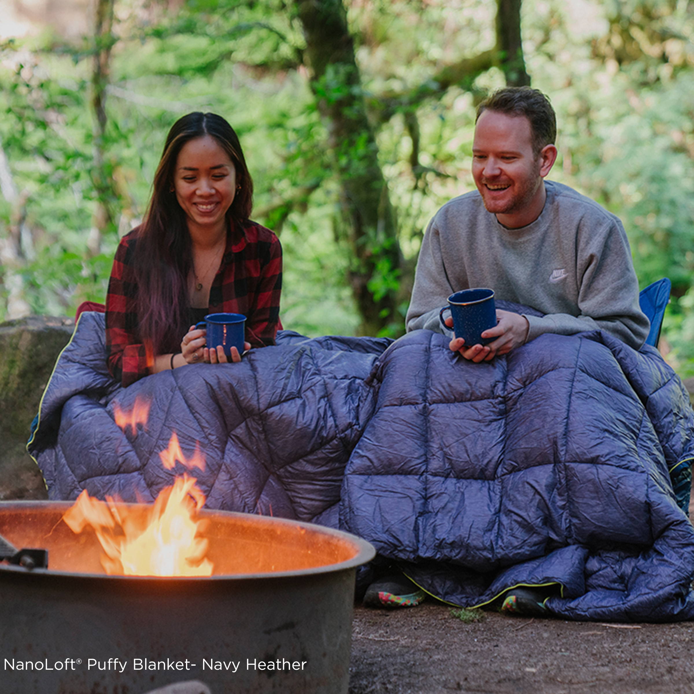 Man and woman wrapped in Rumpl Blanket in Front of Campfire