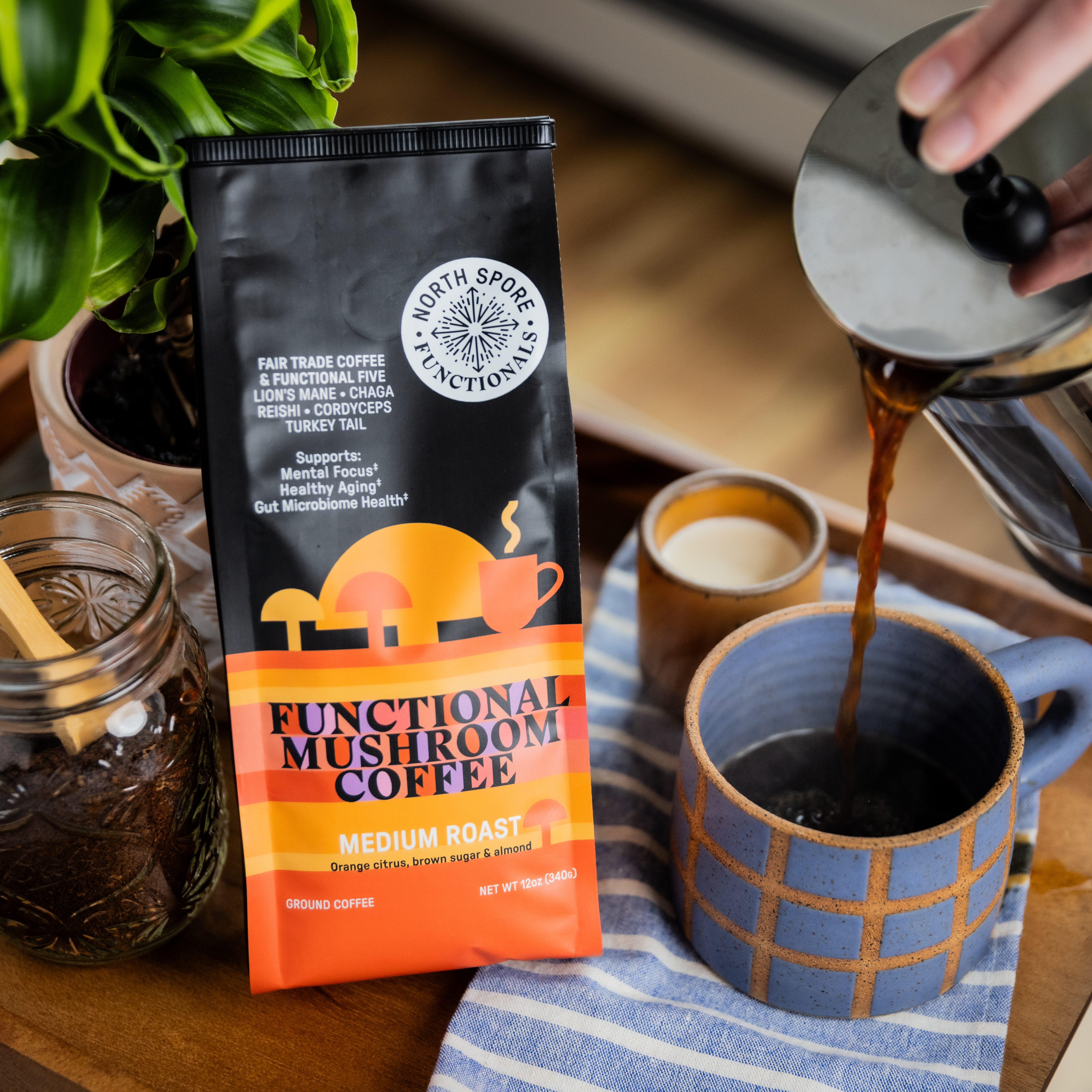 Bag of functional mushroom coffee with cup and plant on a table.