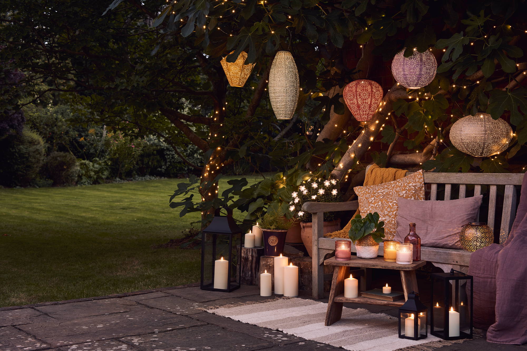 A garden party setting with colourful hanging solar lanterns, LED candles and fairy lights.
