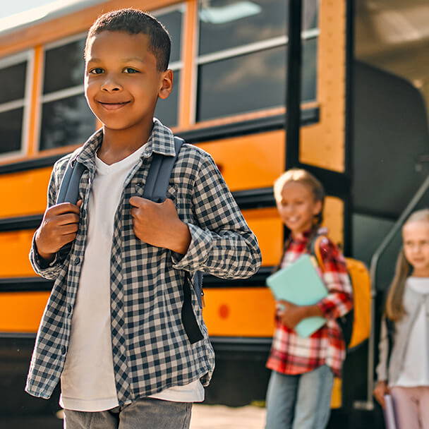 Child getting off school bust with smile on his face