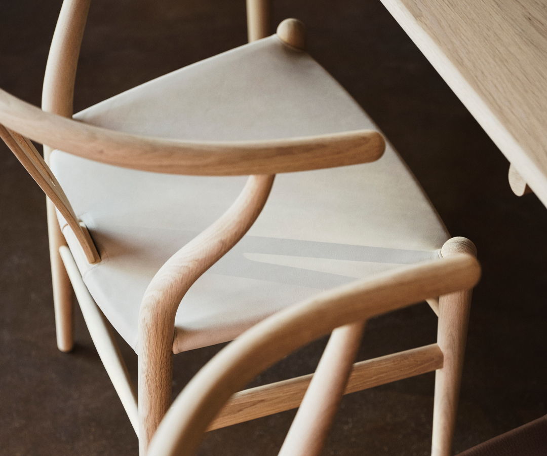 Wooden CH24 Dining chair by Carl Hansen with a minimalist design next to a table.