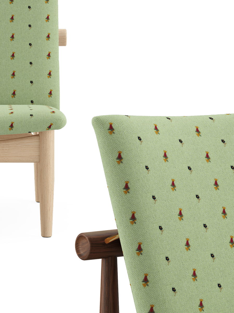 Green upholstered chair with decorative patterns and wooden legs.
