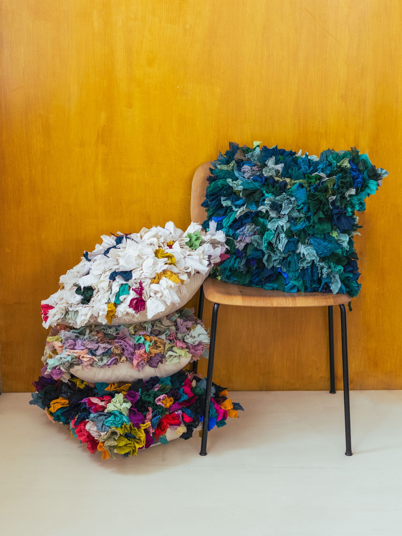 A chair with colorful decorative pillows stacked beside it.