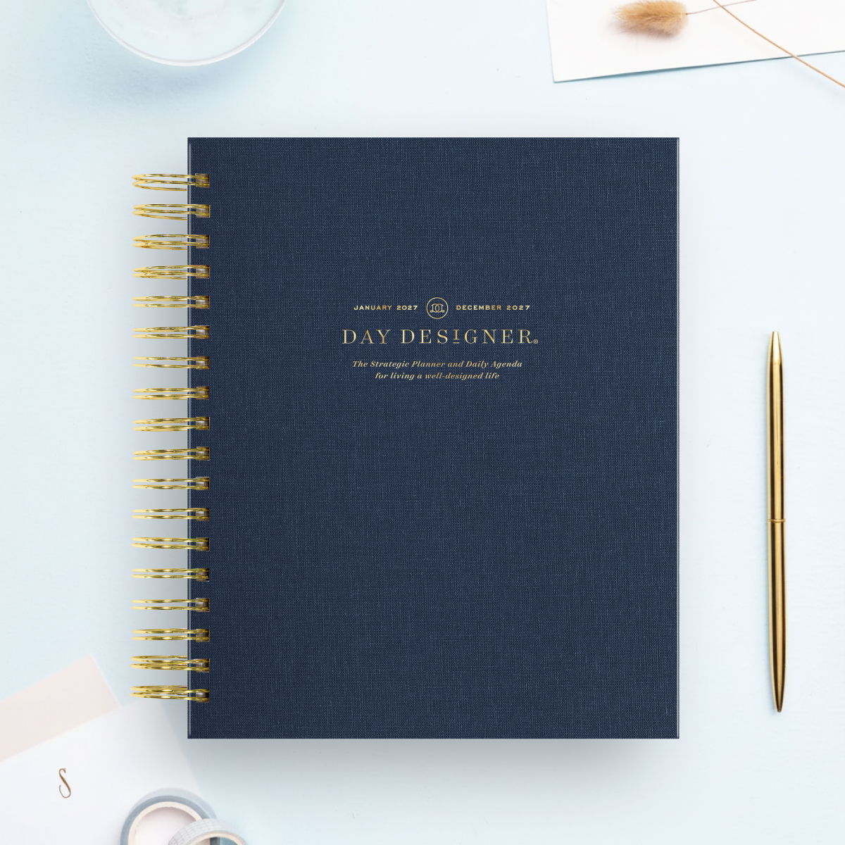 2027 day designer planner featuring navy cover, gold binding and pen, light blue background
