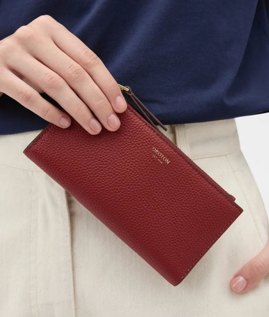 A person holding a red leather wallet.