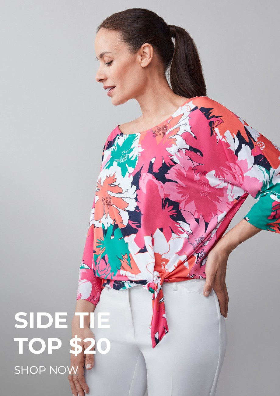 Woman wearing a colorful floral side tie top with white pants.