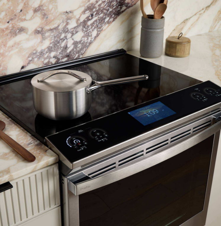 Modern kitchen stove with a pot on a glass cooktop.