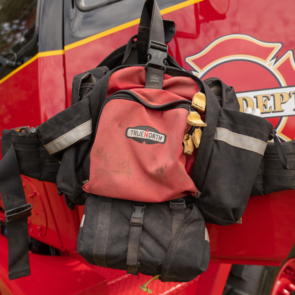 Firefighter's equipment bag hanging on a red fire truck.