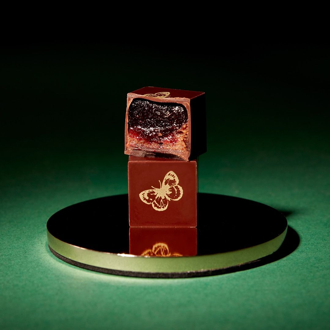 Stacked chocolate cubes on a reflective surface against a green background.