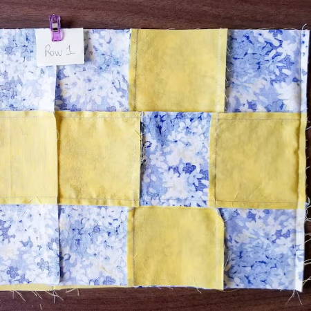 piecing different blocks with yellow and blue fabric together for a quilt