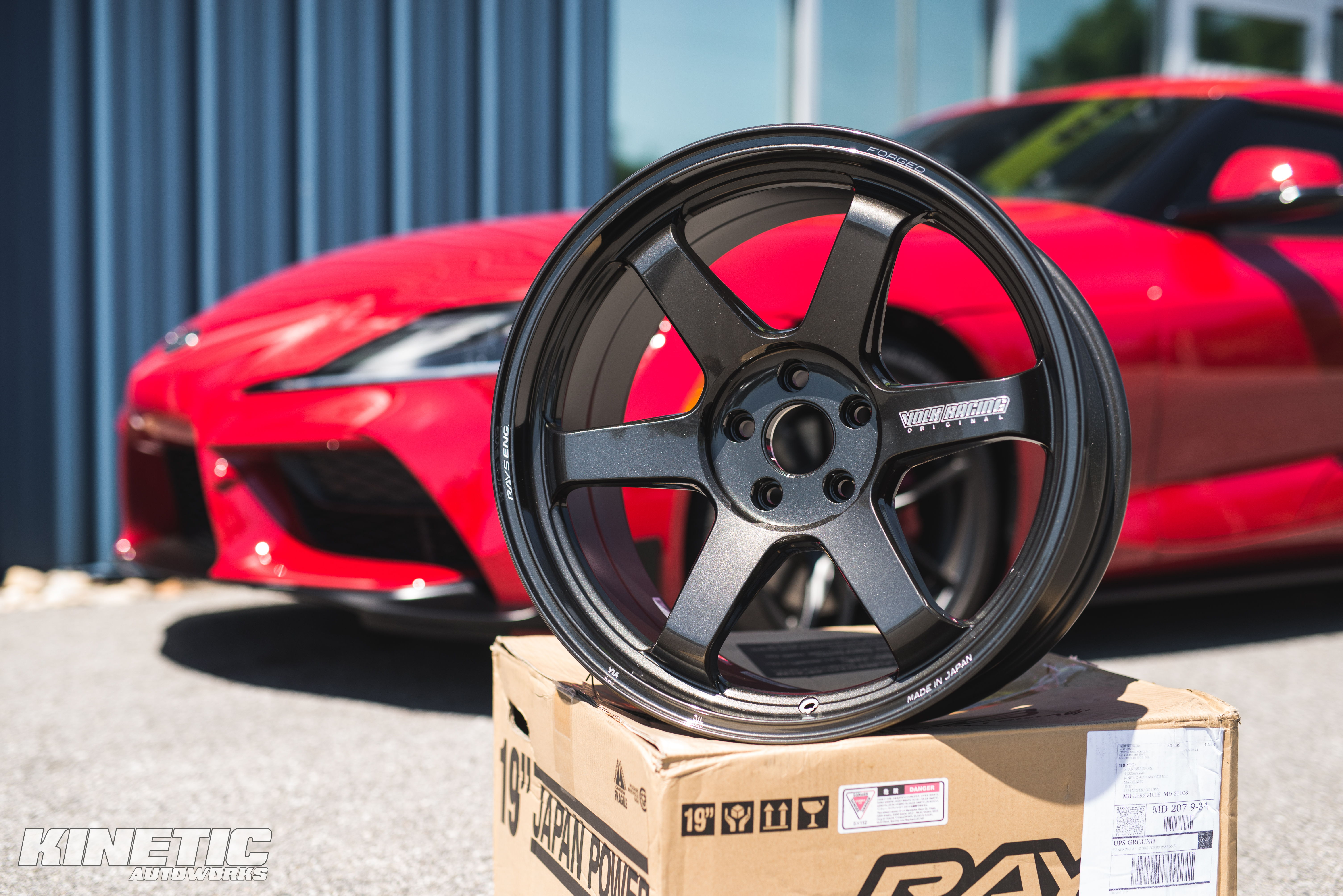 Aftermarket wheel displayed in front of a red Toyota Supra at Kinetic Autoworks