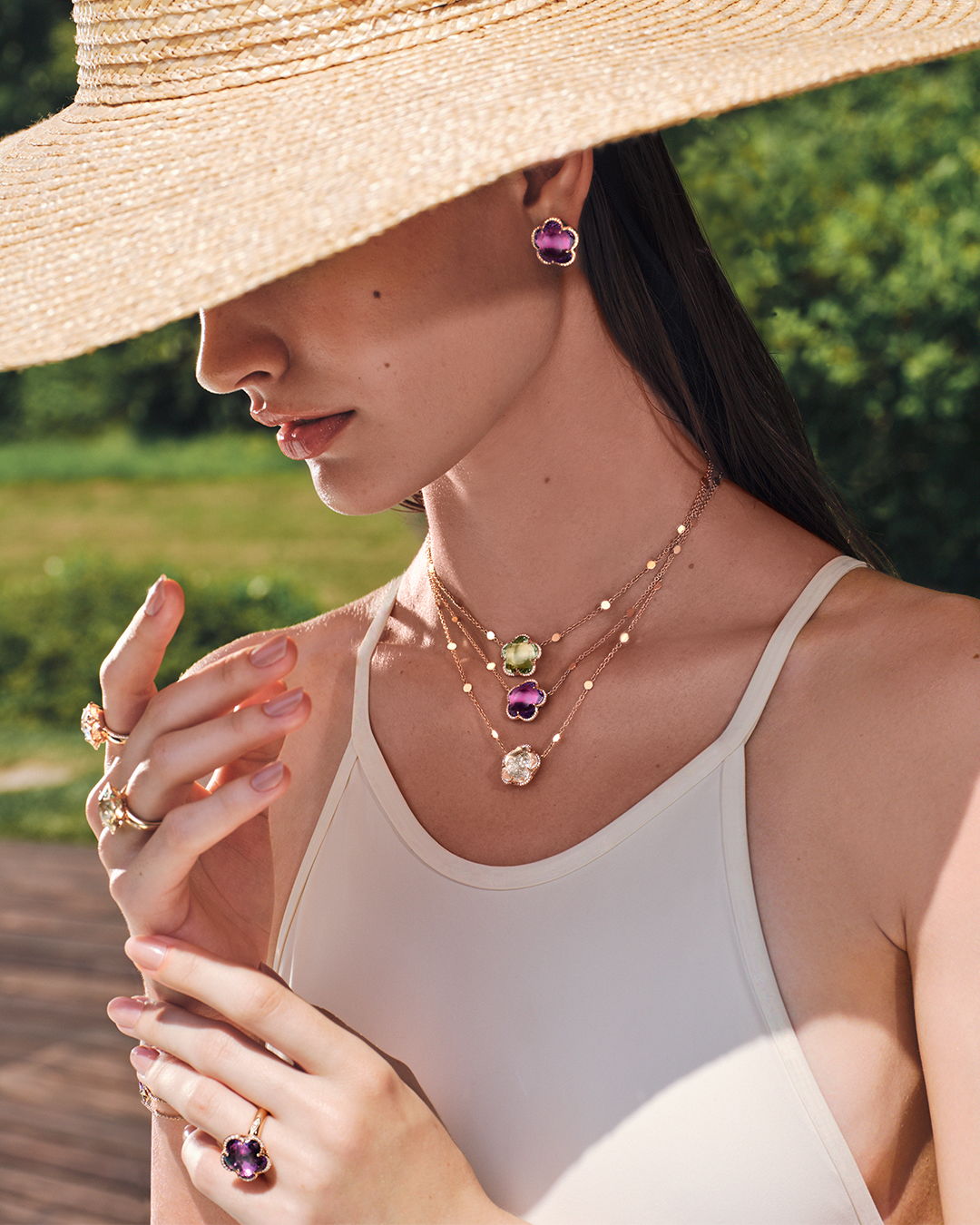 Woman wearing jewelry and a wide-brimmed hat outdoors.