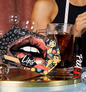 Beauty products with a drink on a table, featuring bold lip art.