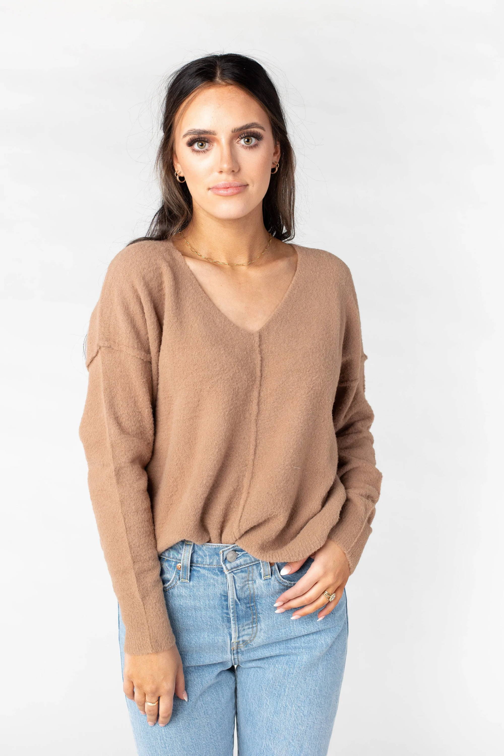 A woman poses in a neutral sweater