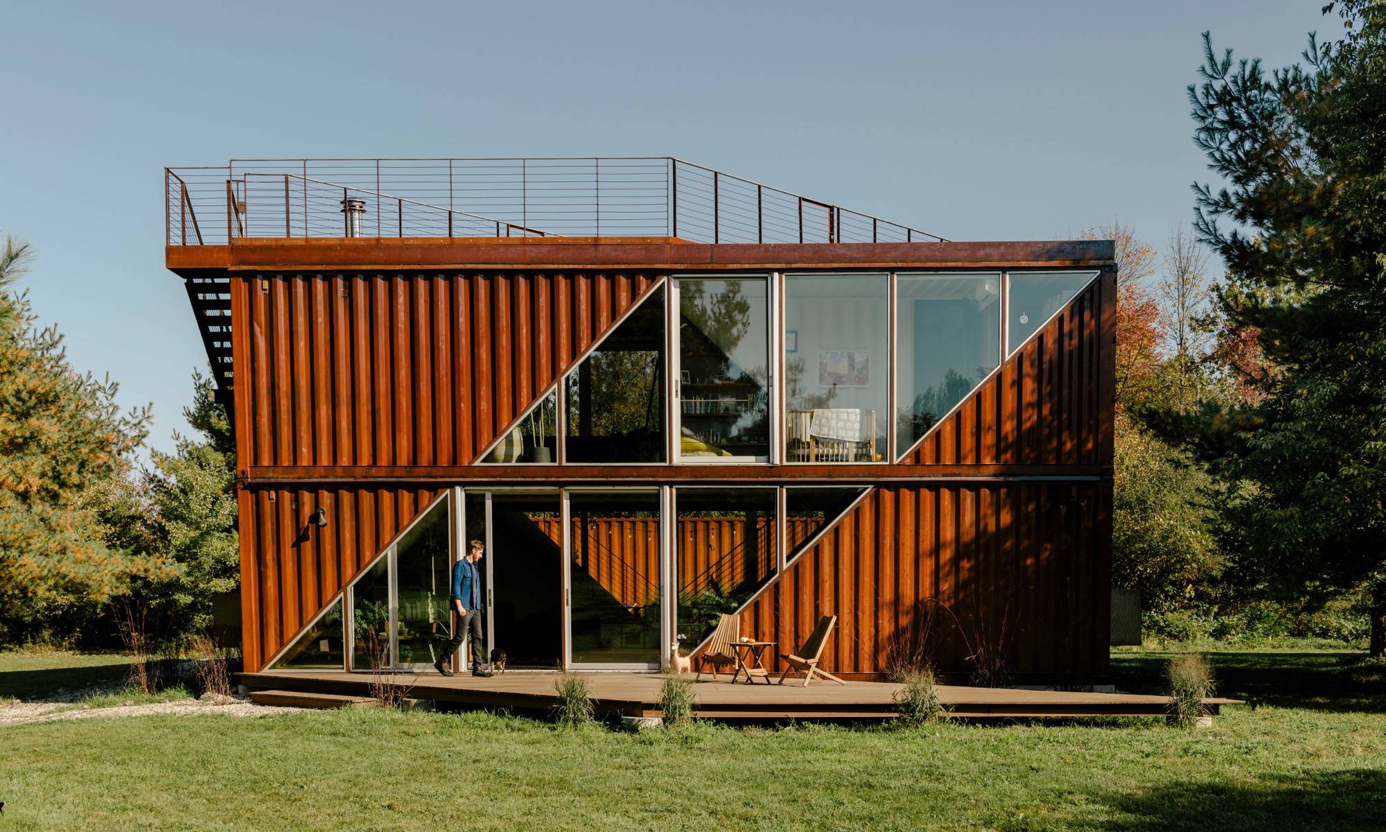 Angular storage container home in burnt rust orange with rooftop deck 