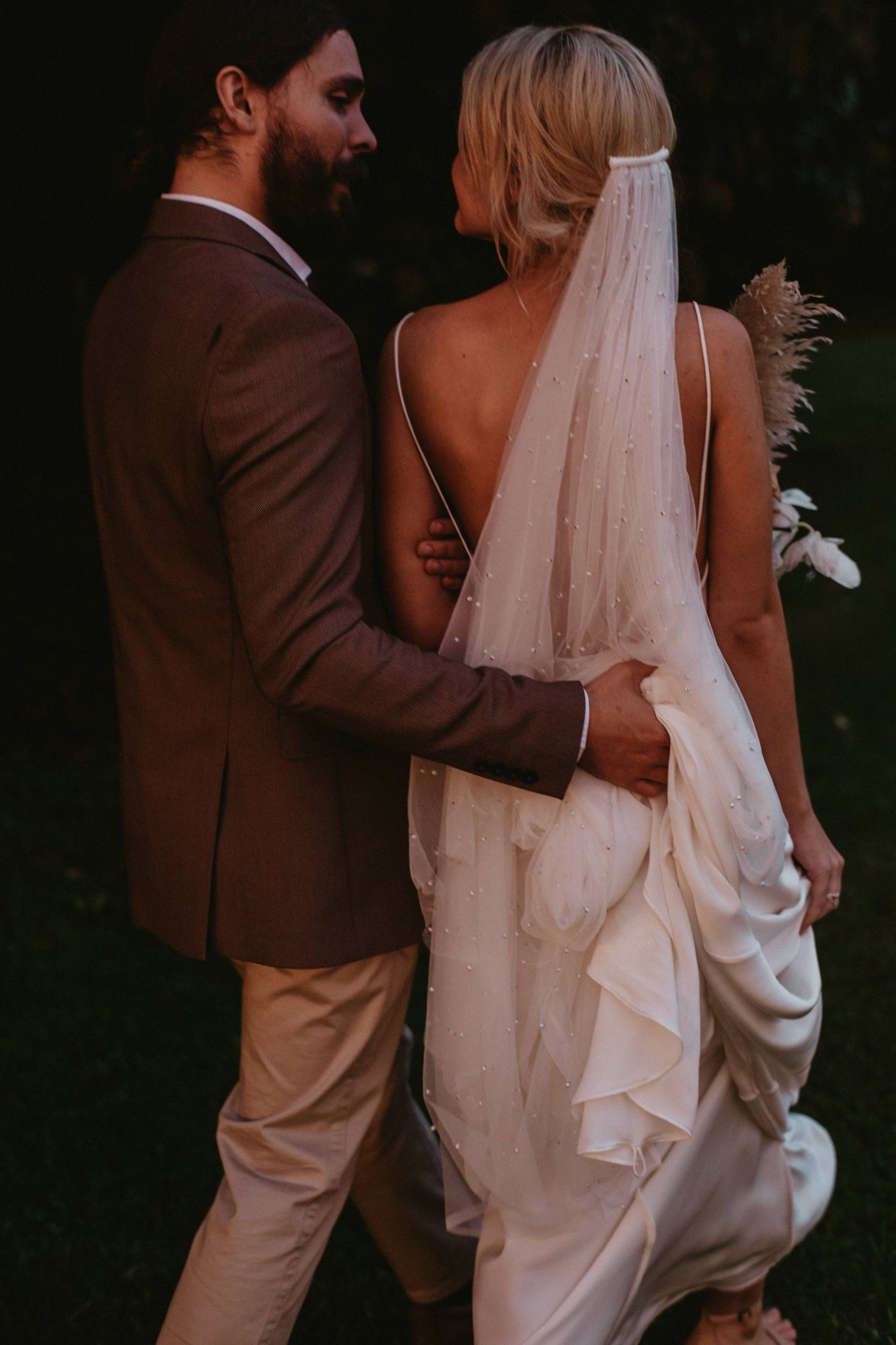 El novio mirando a su nueva esposa sosteniendo su vestido y velo