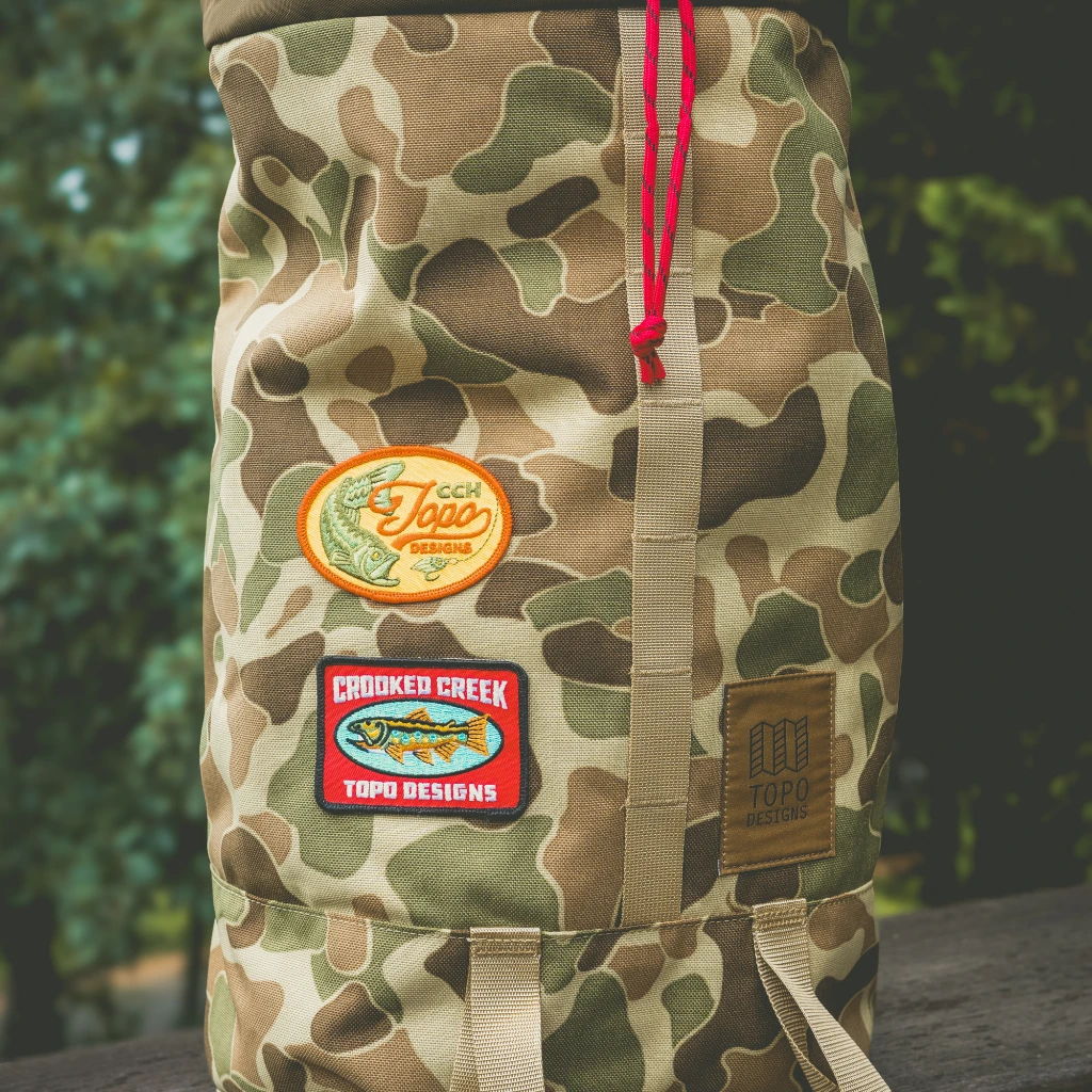 Camo backpack with patches and red drawstring.