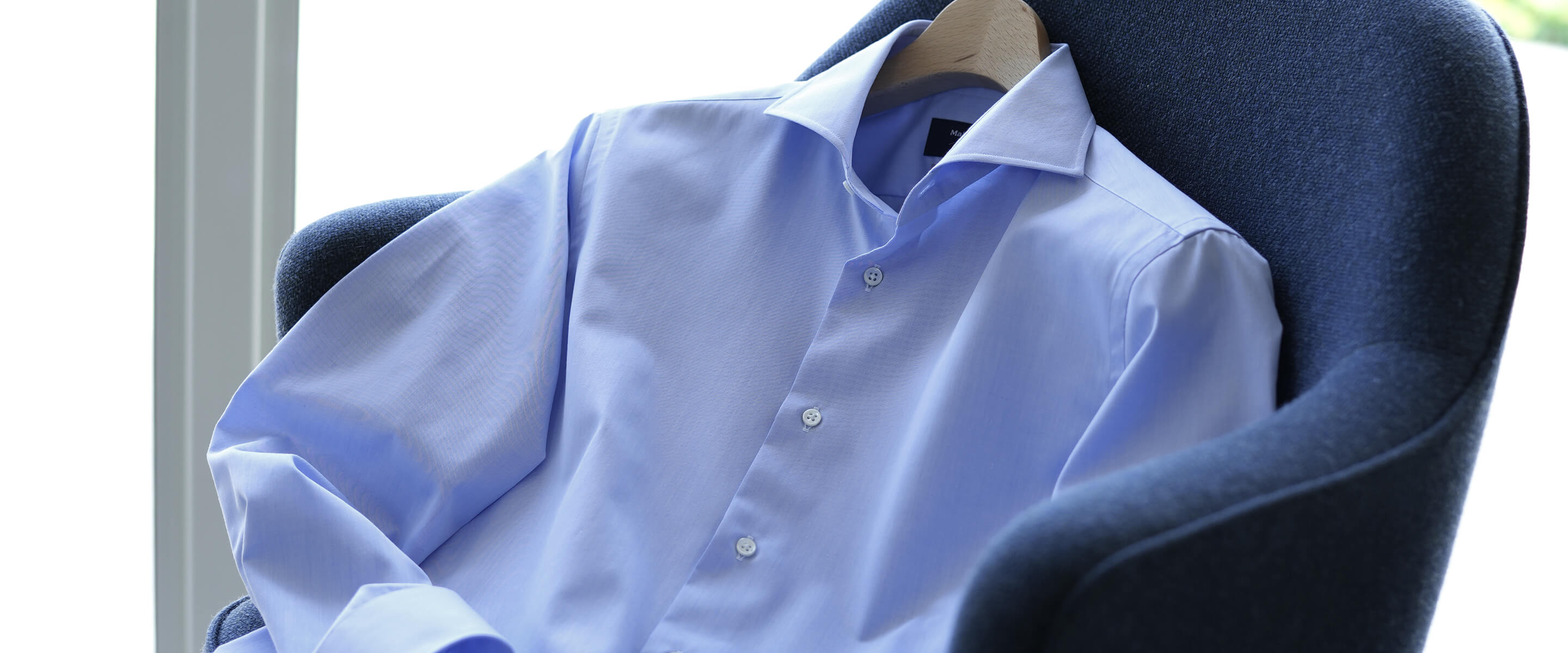 A light blue dress shirt draped over a chair.