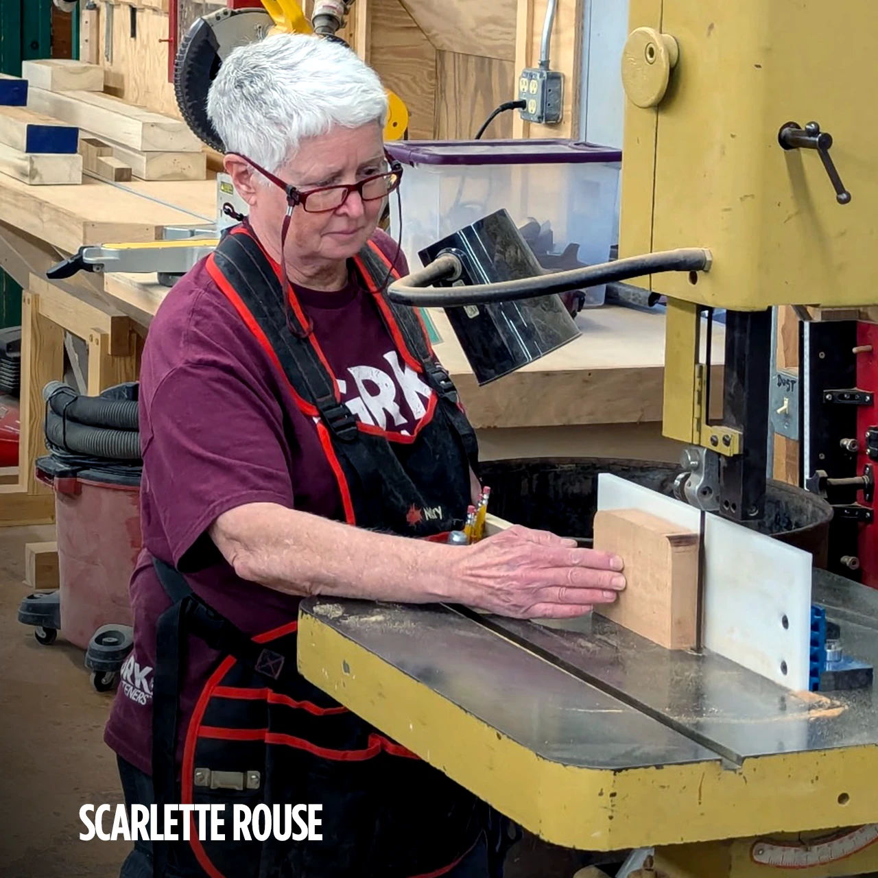 Woman using a bandsaw in a woodworking shop.