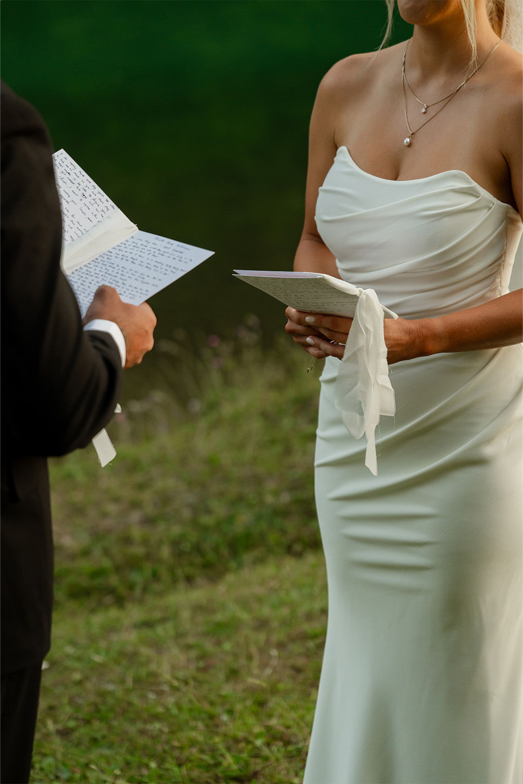 Bride and groom exchanging vows outdoors, with a natural green backdrop.