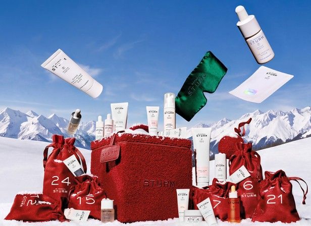 Assorted skincare products displayed on snow with mountains in the background.