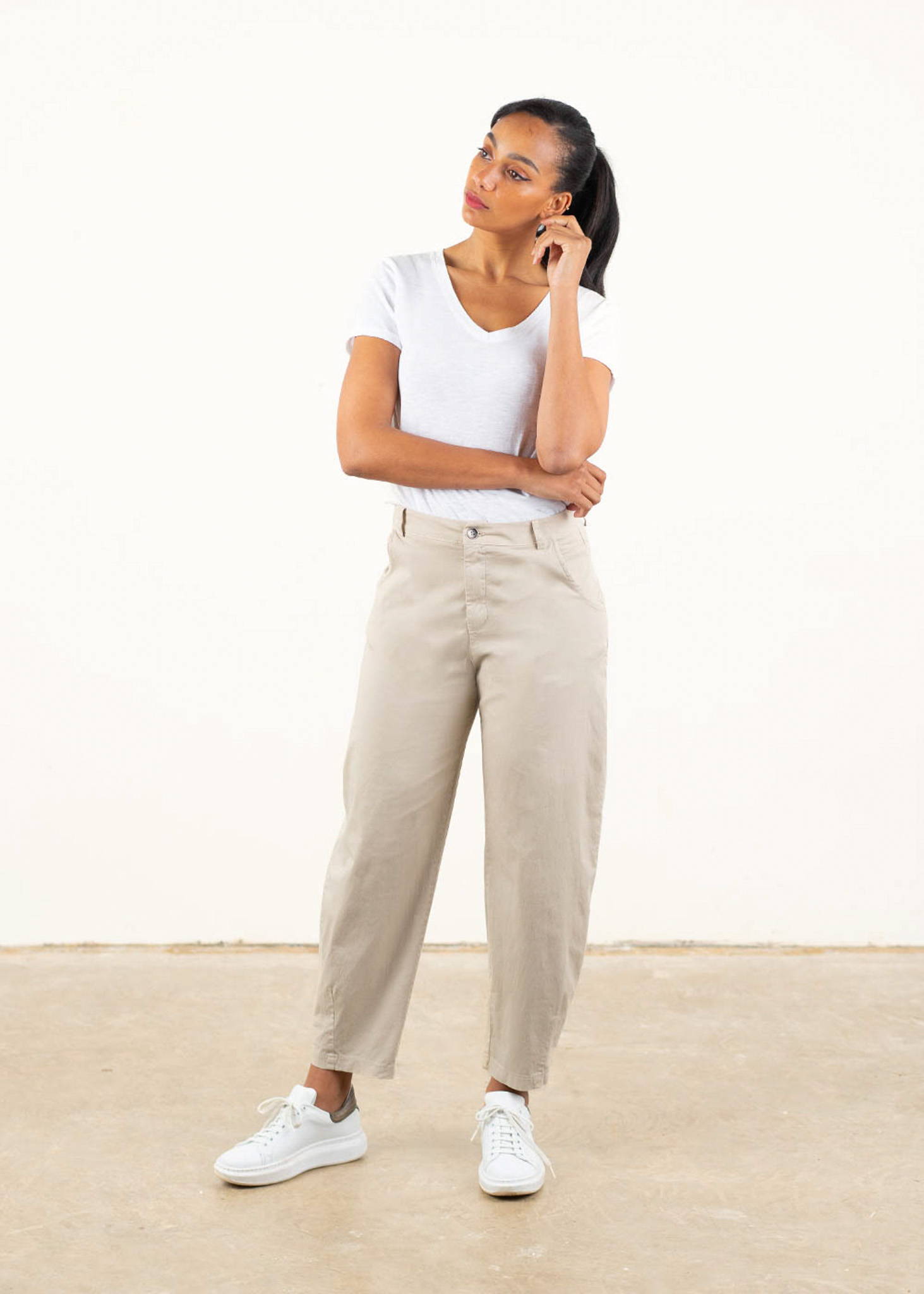 A model wearing a white short sleeved t shirt with oatmeal balloon leg trousers with white trainers