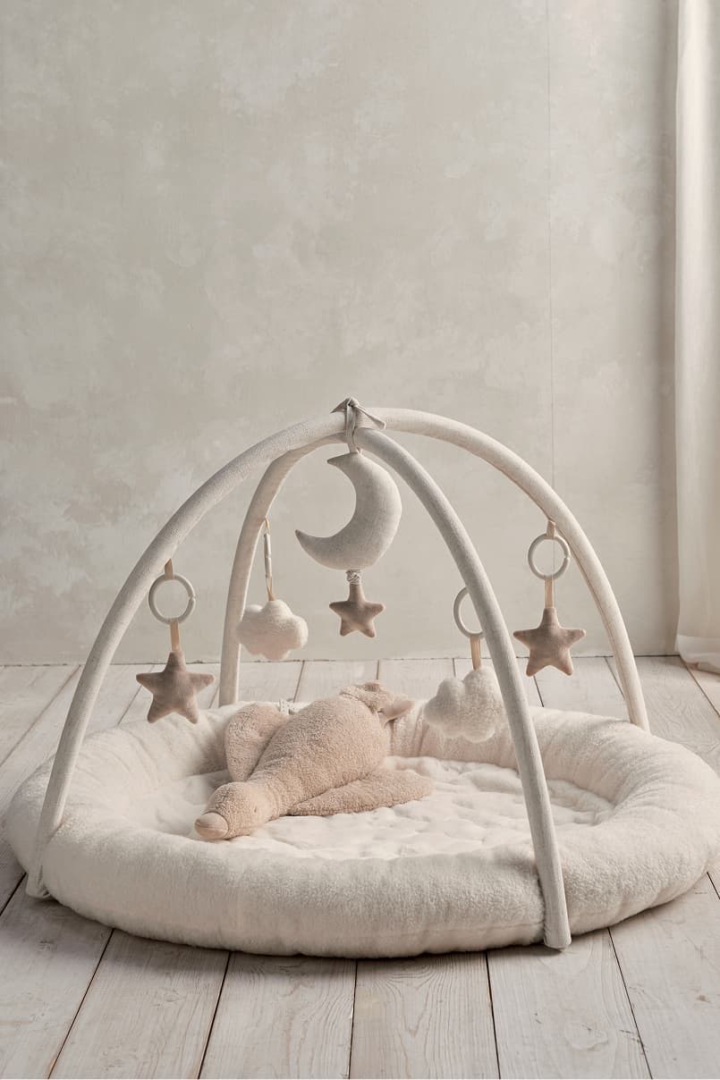 Baby play mat with hanging toys in a soft, cozy environment.